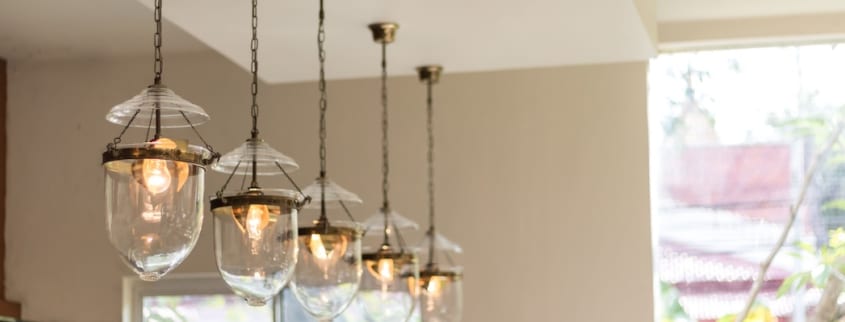 Cinq luminaires en verre sont suspendus dans une cuisine pour fournir une lumière chaude et abondante