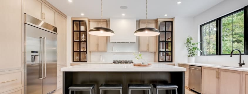 A modern kitchen with a central island, wood cabinets and a plaster range hood
