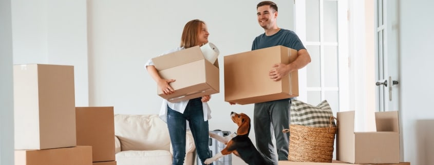 Un couple emménage avec ses boîtes et leur chien dans leur nouvel appartement