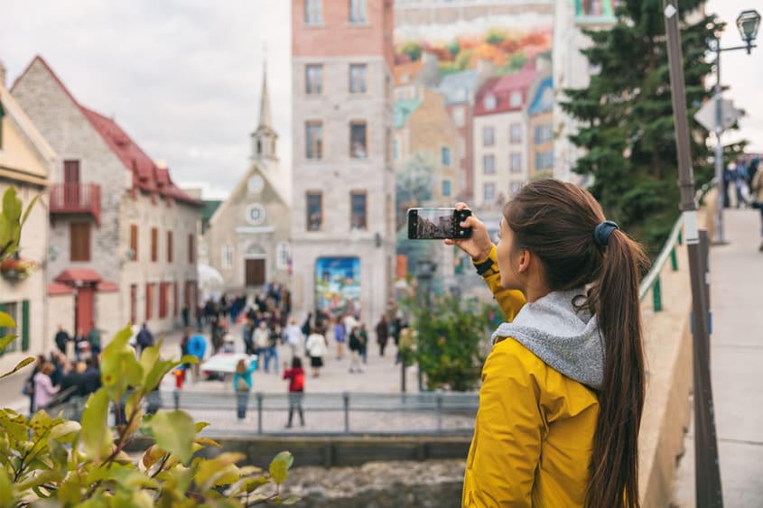 A woman takes a picture of Place Royale’s mural in Québec City