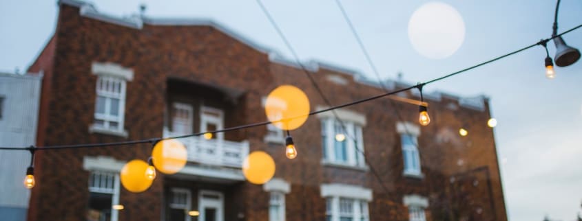 Des lumières suspendues dans la rue devant un immeuble en briques