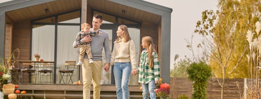 Man holding his baby walking with his wife in front of their summer home
