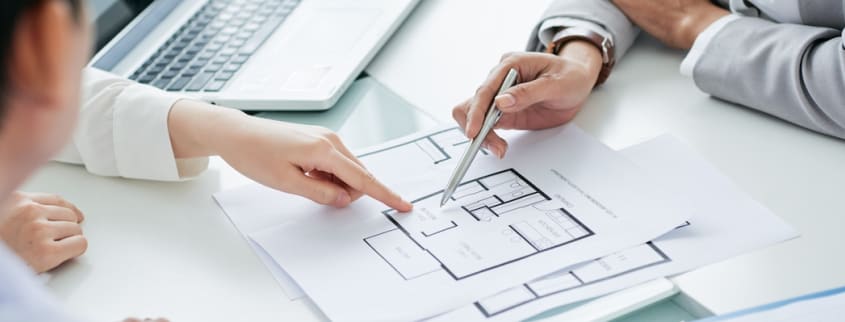 People pointing at a floor plan for a new house