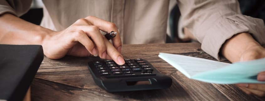Woman typing on a calculator while holding papers