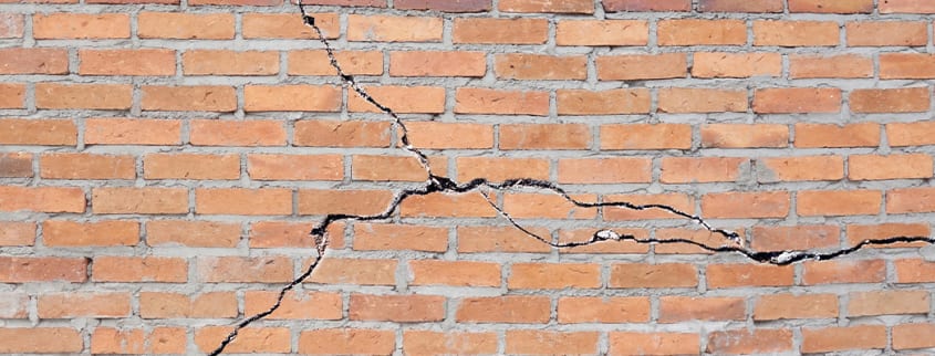 Fissures dans la fondation d'un mur en brique