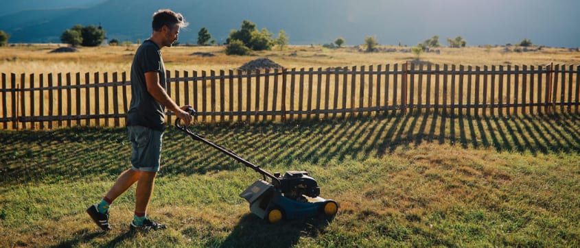 Homme tondant la pelouse sur son terrain en prévision de la vente