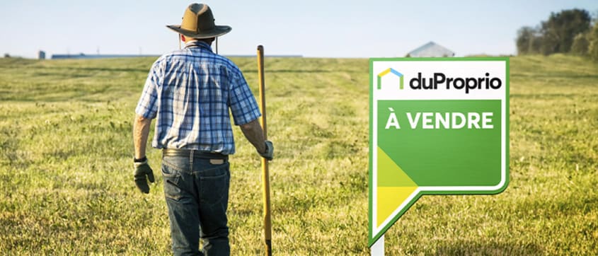 DuProprio sale sign in a field with a worker by its side