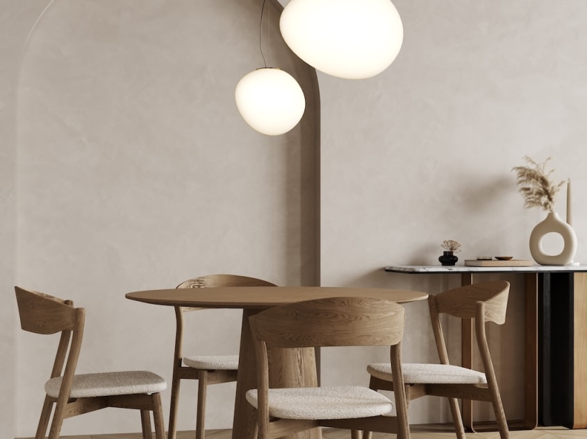 Salle à manger moderne aux murs de béton beige avec arc de cercle, duo de luminaires tendance, table et chaises