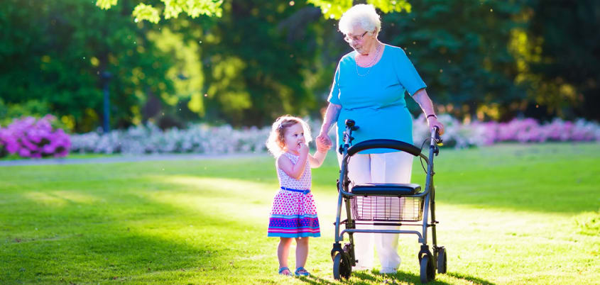 Grand-mère en marchette avec sa petite-fille sur la pelouse d'une maison