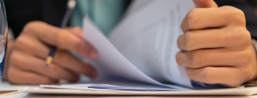 Une personne regarde des documents de près et les signent