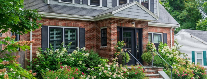 Une maison en briques entourée de plantes et de fleurs