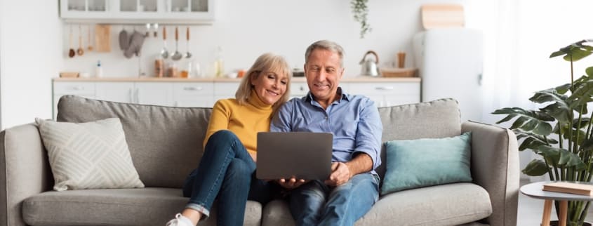 Un homme et une femme regardent un ordinateur en souriant
