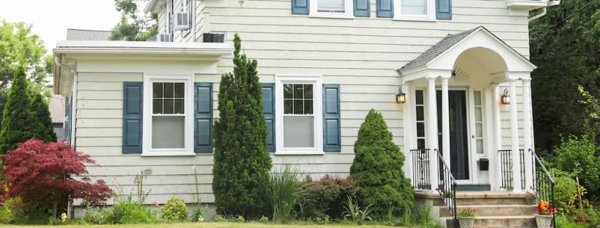 Une maison à étage de couleur beige avec des volets bleus