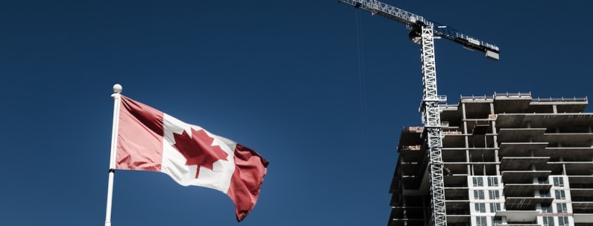 Un drapeau du Canada flotte devant une tour immobilière en construction