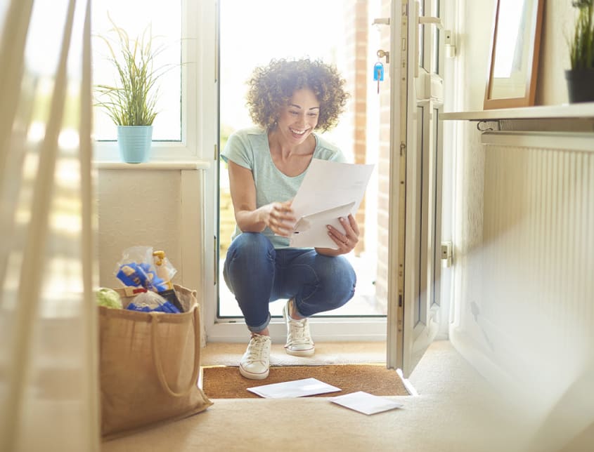 Woman consulting a document at the entrance of her property