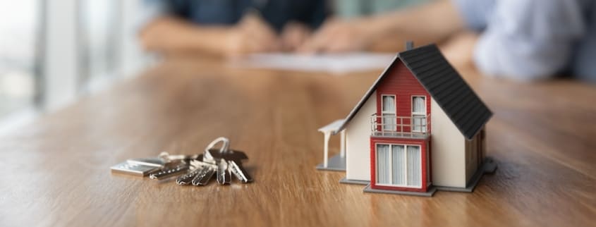 Une maison miniature et un trousseau de clés sont sur une table