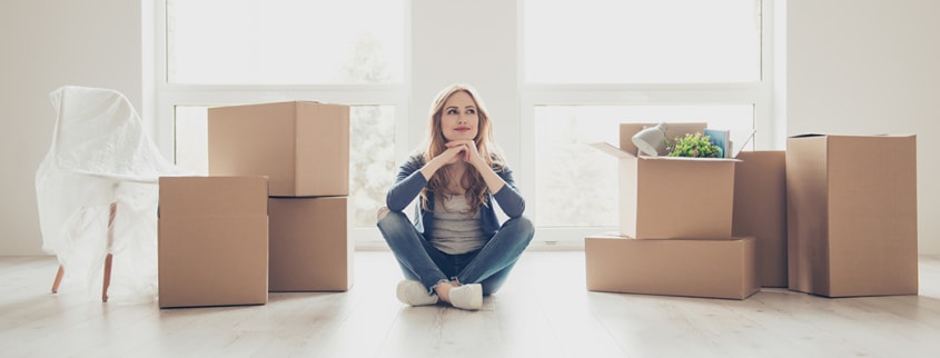 Woman sitting in her new condo with moving boxes
