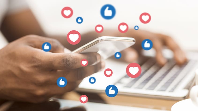 Man holding a phone with floating social media reactions