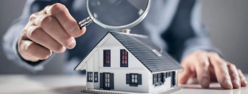 Personne regardant une maison avec une loupe