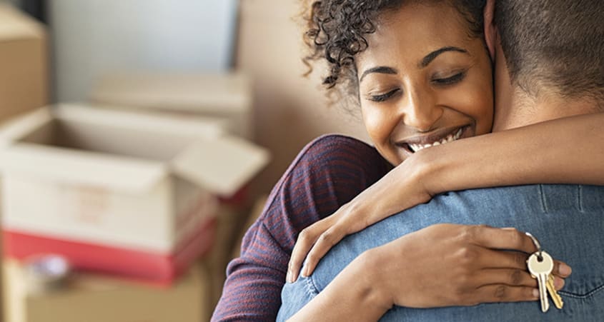 Woman holding the keys to her new house while embracing her partner