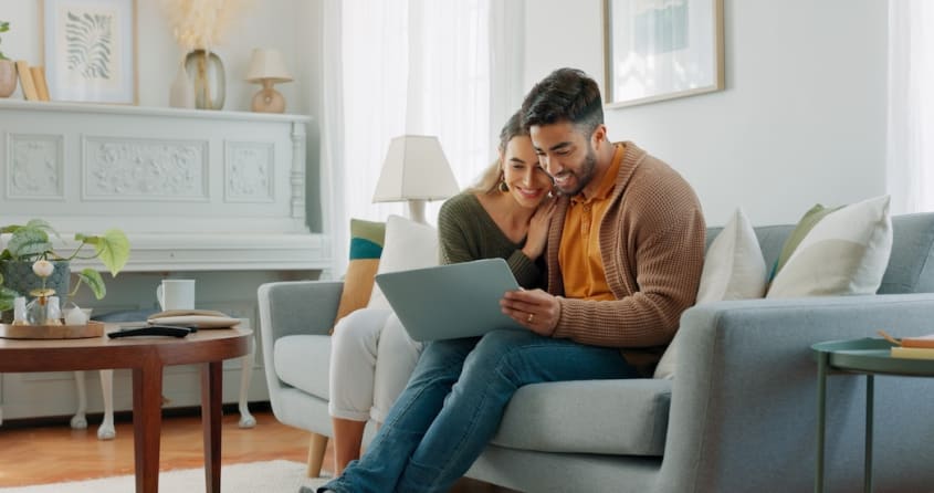Couple qui regarde un ordinateur et qui consulte les annonces immobilières de propriétés à vendre