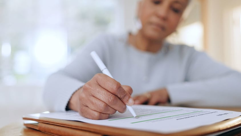 Person holding a pen and filling out a document