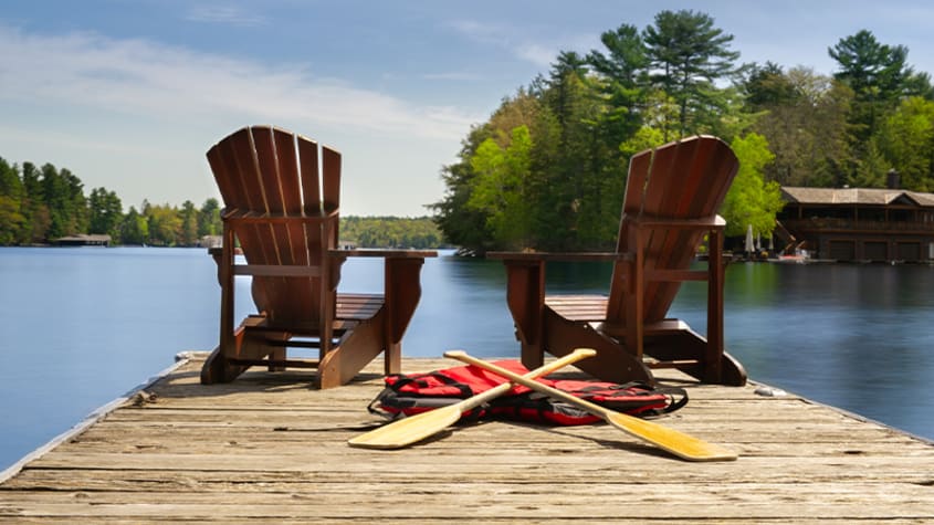 Adirondack chairs on a quay on a lake