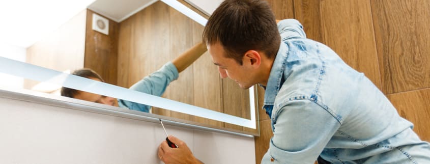 Man installing a new mirror in the bathroom