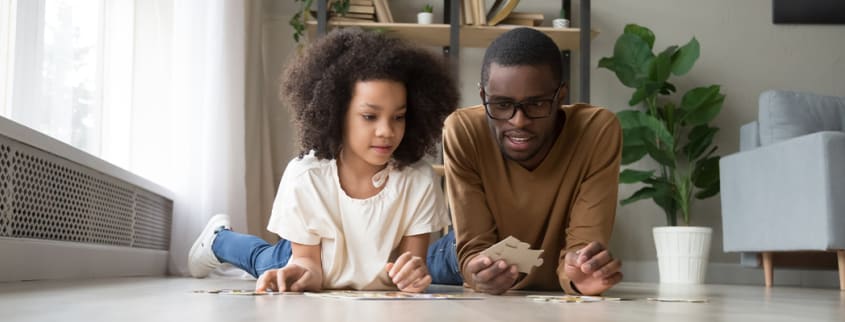 father and daugther making a jigsaw puzzle on the floor