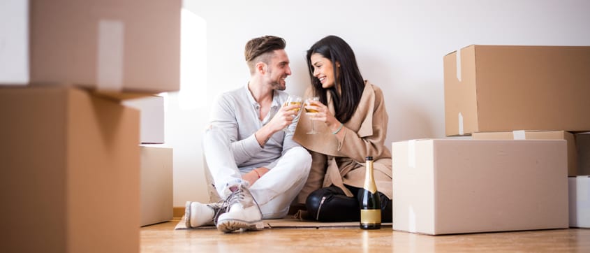 Couple célébrant avec du champagne autour de boîtes de déménagement