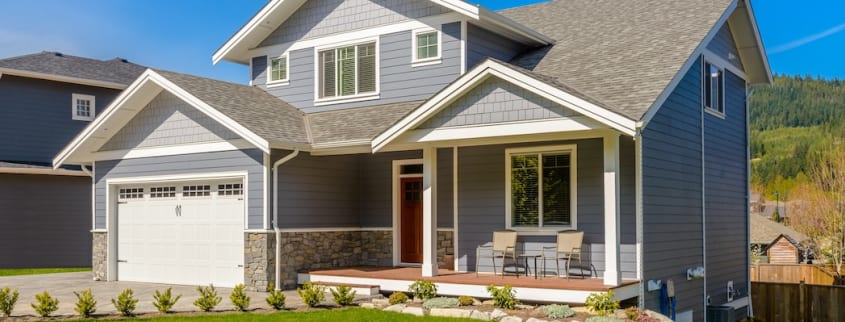 A blue house with a garage and a front porch