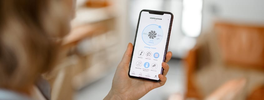 Femme contrôlant la ventilation de sa maison à partir de son téléphone