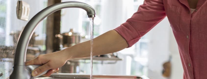 Woman shutting the faucet in the kitchen