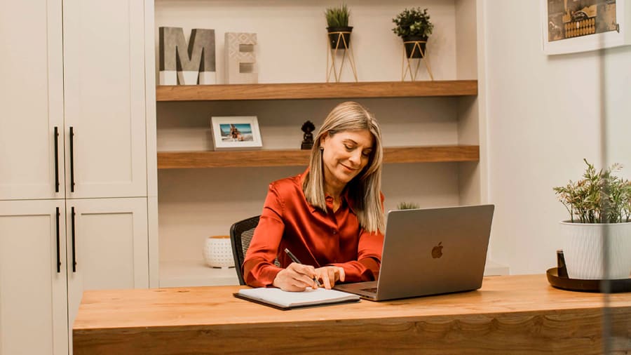 A blonde woman working on her laptop in a home office